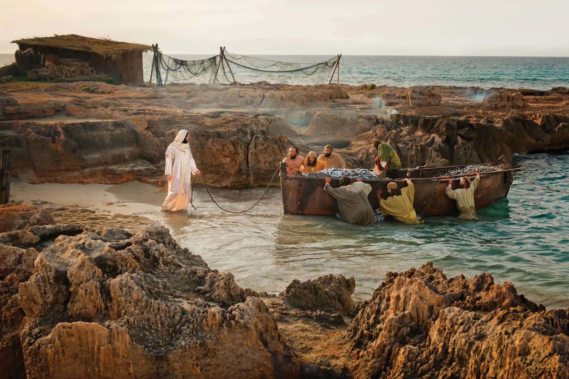 Christ standing at the water's edge as fishermen haul in a laden net